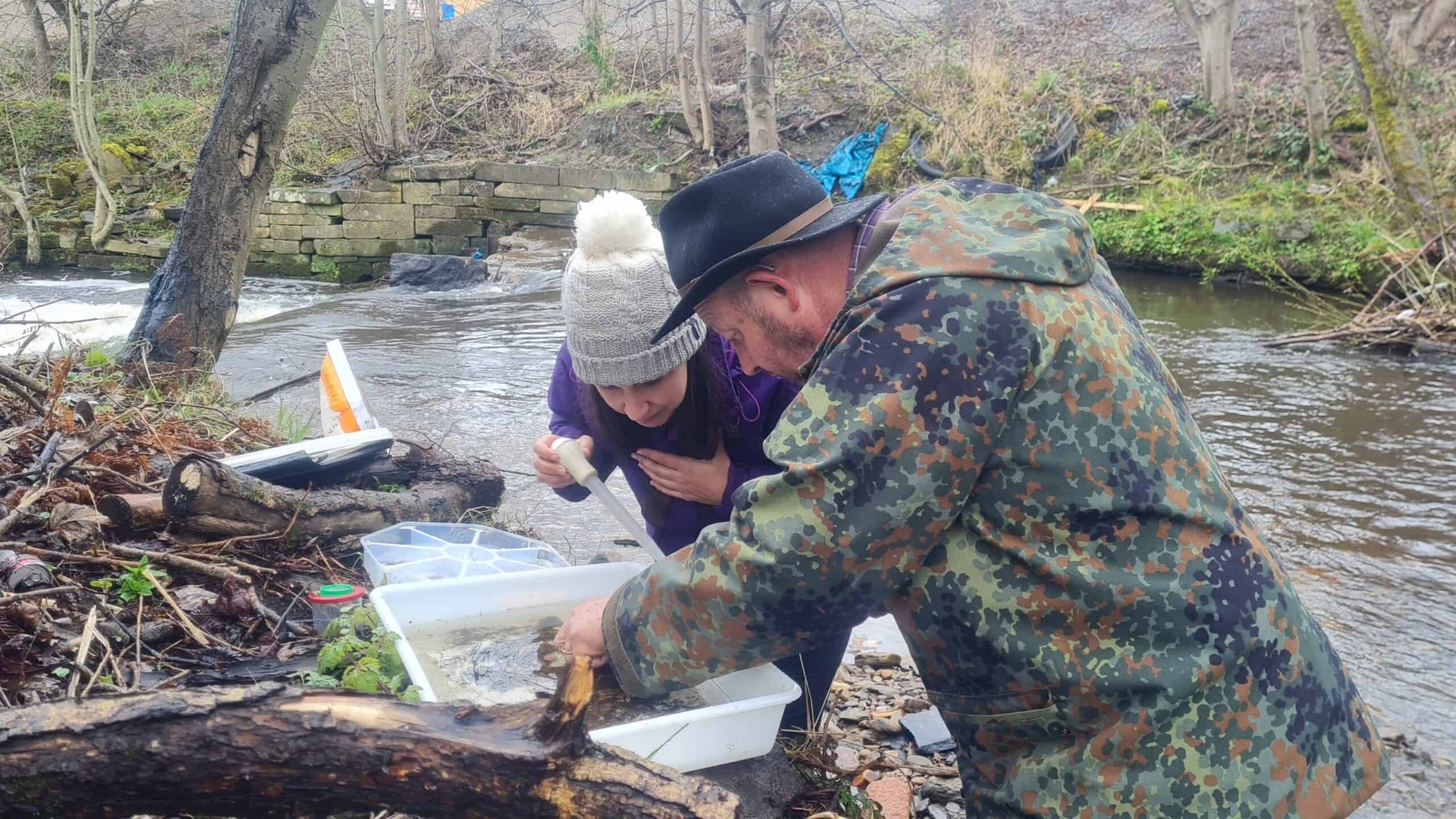 Two people looking at a sample of river bugs