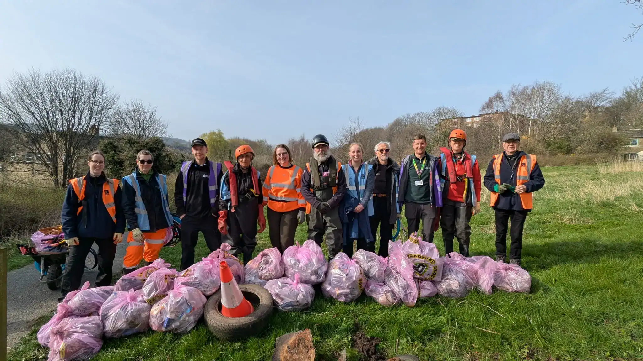 Volunteers standing in front of large pile of litter collected from river.
