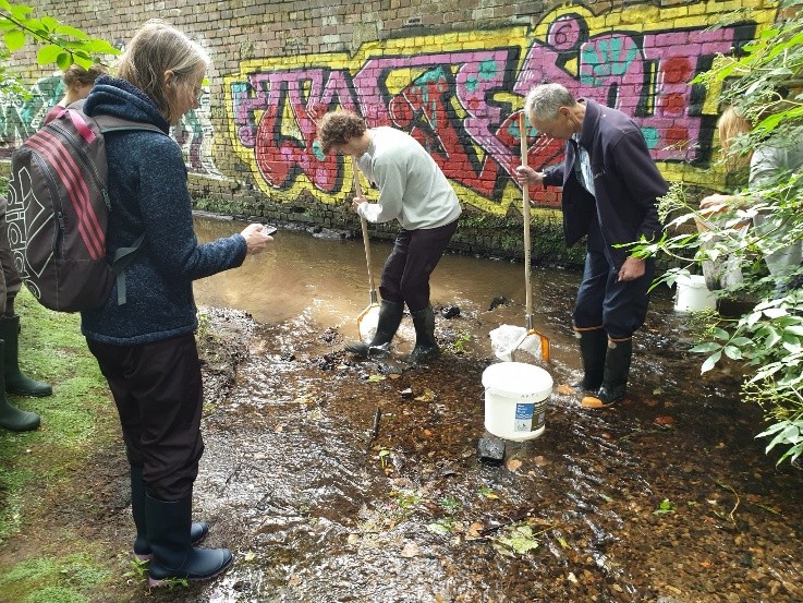 Three people in a river taking samples
